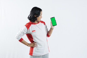 Young Asian woman looks happy in Indonesian Independence Day attire. woman shows her mobile phone with green screen suitable for advertising