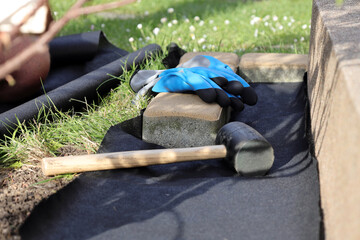Laying an anti-weed mat in the garden together with paving stones and decorative pebbles