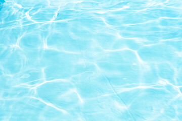 Blue water with ripples on the surface. Defocus blurred transparent blue colored clear calm water surface texture with splashes and bubbles. Water waves with shining pattern texture background.