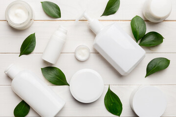 Organic cosmetic products with green leaves on wooden background. Flat lay