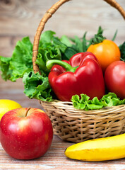 Vegetables and fruits in the basket and on the wooden table. Close-up.