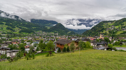 Fototapeta premium panorama from village Schruns in Montafon, Vorarlberg, with small alpine houses between forested steep slopes and flowered meadows. in the mountains from Rhätikon, at the border to Switzerland, cloudy
