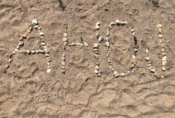 The word AHOJ spelled out with pebbles on the sand