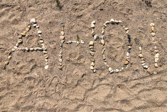 The word AHOJ spelled out with pebbles on the sand