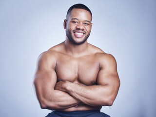 Black man, arms crossed and shirtless in studio with smile for healthy body, portrait and fitness with confidence. Bodybuilder, athlete and power with wellness and arm strength on blue background