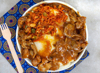 Traditional South African street food, gizzards and pap or maize meal and Chakalaka in black bowl...