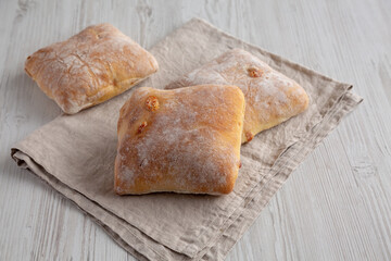 Homemade Cheese Ciabatta Buns on a white wooden background, side view.