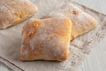 Homemade Cheese Ciabatta Buns on a white wooden background, side view.