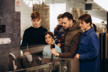 A young large family chooses a shower system in a store