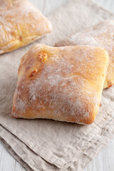 Homemade Cheese Ciabatta Buns on a white wooden background, side view.