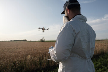 Man operates agricultural drone. Modern technologies in agriculture. Industrial drone flies over a green field and sprays pesticides to increase productivity and destroys harmful insects. Technologies