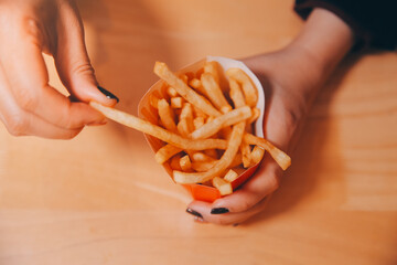 Asian woman holding french fries and eating happily in restaurant