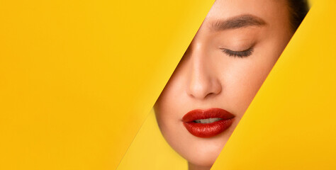 A close-up shot of a woman face with vibrant red lipstick standing out against a bright yellow...