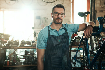Portrait, serious and man with bike for technician career, small business and entrepreneur in maintenance garage. Mature guy, bicycle mechanic and professional skills for repair in service workshop