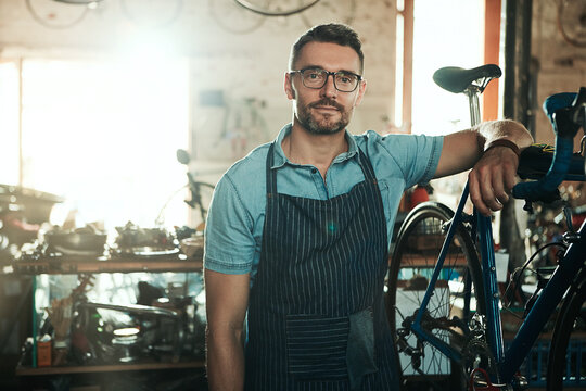 Portrait, serious and man with bike for technician career, small business and entrepreneur in maintenance garage. Mature guy, bicycle mechanic and professional skills for repair in service workshop
