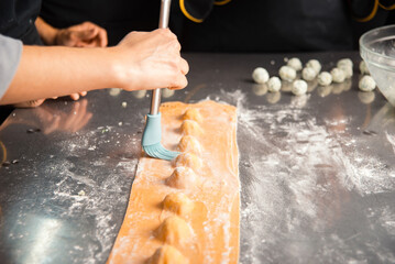 Hands skillfully crafting fresh ravioli pasta in a professional kitchen, highlighting culinary expertise