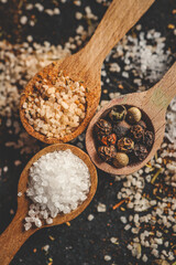 Wooden spoons with different spices on a black background, banner