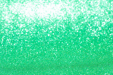 Close-up of sparkling green glitter texture creating a vibrant and festive background with shimmering lights and reflective surfaces, perfect for celebrations and decorative projects.