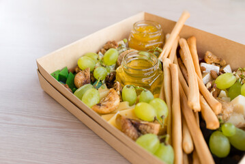 Set of traditional Italian breadsticks, delicious crispy grissini sticks, honey, grapes, cheese and figs. Catering box	