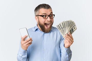 A man is shown holding a cell phone in one hand and a stack of money in the other. He appears to be...