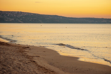 Golden sunrise on serene beach, gentle waves, tranquil shoreline peaceful and picturesque scenery