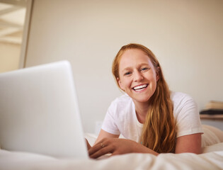 Fototapeta premium Girl, laptop and portrait for networking while on bed, searching and happy for browsing for movie. Home and smile at streaming site for entertainment, online in bedroom and post blog on website