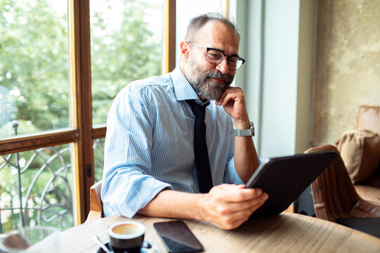 Businessman in a cafe working with tablet and drinking coffee