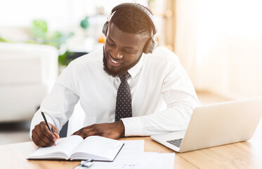 Fototapeta premium Looking for inspiration. Creative black businessman listening to music with wireless headset at workplace, planning future