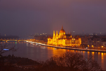 Obraz premium Glowing lights of Budapest's Parliament Building reflect on the Danube River at night. Scenic and captivating.