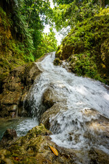 Fototapeta premium Blue Hole Waterfalls in Jamaica, pristine beautiful falls with vibrant blue and green colors.