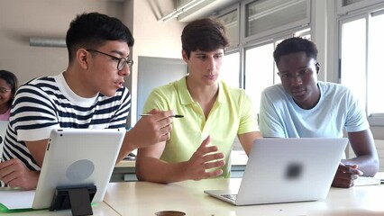 Group of diverse male college students working with a laptop as a team in class - Powered by Adobe