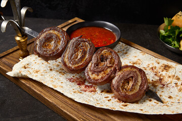 Delicious Grilled Beef and Fat-Tail Lamb Roll Kebabs with Sauce on Rustic Bread