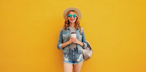 Summer stylish happy young woman with cup of coffee wearing summer hat on yellow background