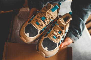 Men's sneakers in hands, unpacking stylish shoes