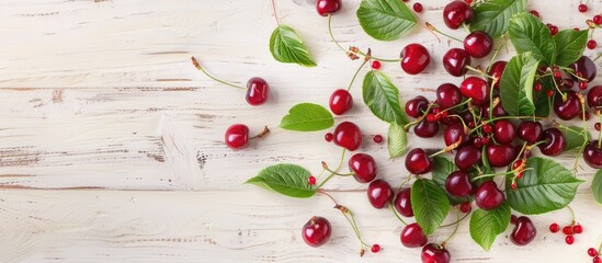 Juicy cherries with vibrant green leaves on a light wooden backdrop, viewed from above with space for text. Capturing the essence of summertime fruits and berries.