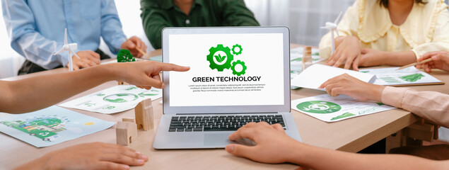 Green technology logo displayed on green business laptop while business team presenting green...