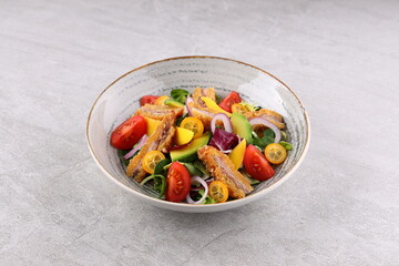 Crunchy thai style chicken salad in bowl over light stone background. Close up view