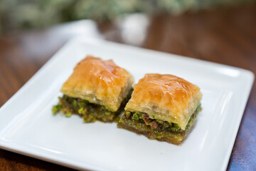 Close up view of two pieces of baklava with pistachio on white plate on a table.