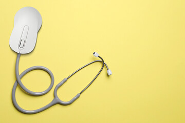Computer mouse with stethoscope on pale yellow background, top view. Online medicine