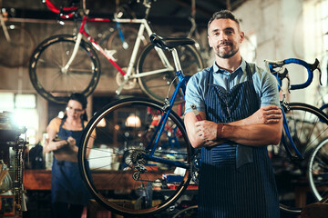 Mechanic, portrait and arms crossed at work in bicycle repair shop or maintenance garage. Bike,...
