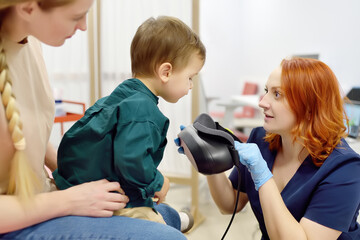 Toddler boy with mom are at appointment with a pediatric neurologist. Neurology doctor is...
