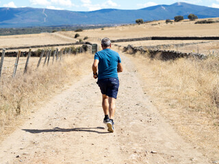 Spanish senior man in fitness wear running running by in nature