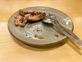 used dinner plates with spoons, forks and the remains of used chicken bones