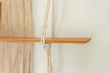 Close-up of macramé knot and wooden shelf detail

