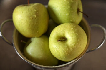 Fresh wet apples in metal colander inside sink, closeup