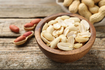 Fresh peanuts in bowl on wooden table, closeup