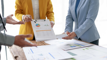 Business meeting with professionals reviewing documents and charts. Team collaboration and discussion in a corporate setting.