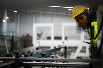 Portrait of African woman worker beautiful face with eye confident and wearing working suite dress and safety helmet at heavy machine in industry factory. Engineer  worker concentrate on workplace.