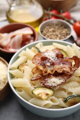 Tasty pasta with bacon and cheese on grey table, closeup