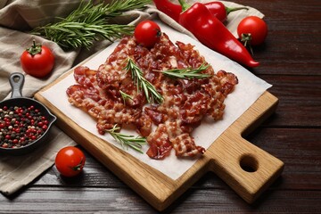 Slices of tasty fried bacon, tomatoes and different spices on wooden table, top view